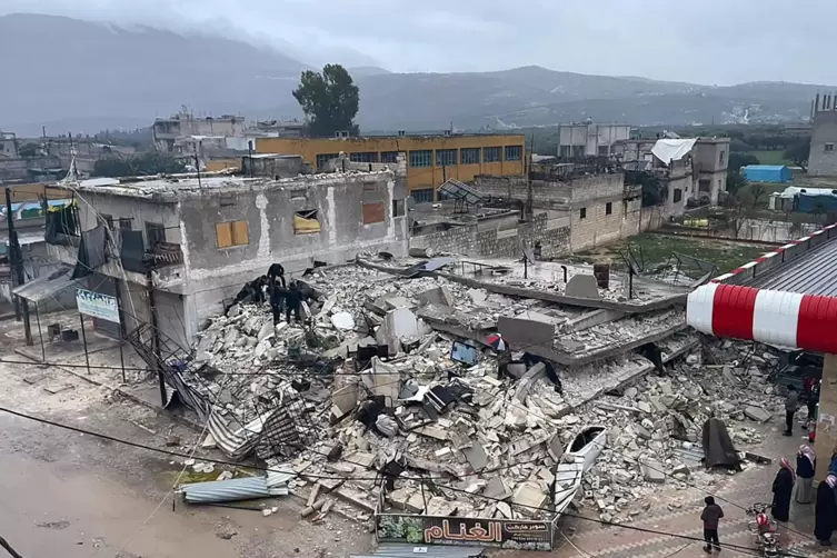 Syrien, Azmarin: Menschen durchsuchen die Trümmer eines eingestürzten Gebäudes in der Stadt Azmarin in der Provinz Idlib im Nord