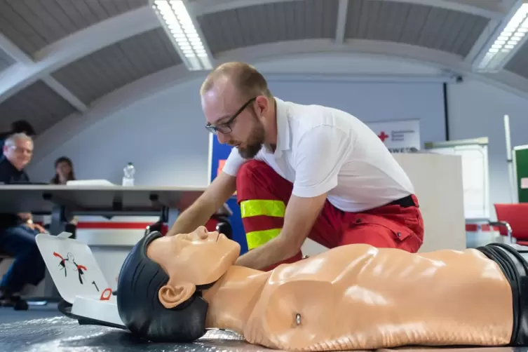 Ein Rettungssanitäter zeigt anhand einer Übungspuppe den Umgang mit einem Defibrillator.