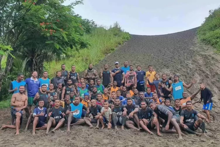 Timo Jankowski im Sand mit Jugendspielern und der legend&auml;ren 7er-Rugby-Mannschaft Fijis, zweifacher Olympiasieger. 