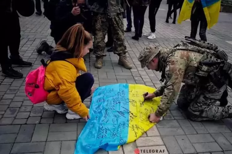 Ein ukrainischer Soldat unterzeichnet am 16. November 2022, nach der Befreiung von Cherson, die ukrainische Flagge. 