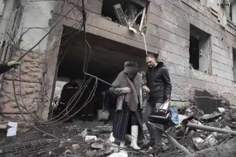 Die Zivilbevölkerung in der Ukraine leidet: Ein Mann hilft in Charkiw einer Frau beim Verlassen eines Wohnhauses, das von einer 