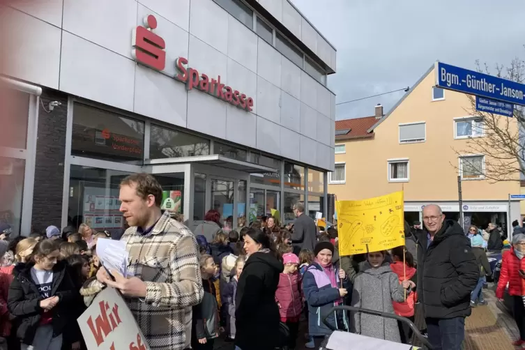 Die Kinder stellen sich vor dem Geb&auml;ude auf, um selbst gestaltete Lesezeichen zu verteilen. Schulleiter Manoel K&uuml;hner sammelt di