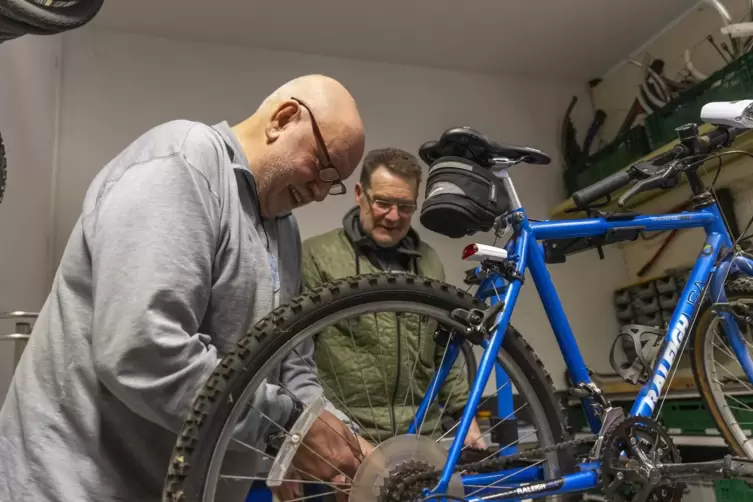 Peter Höchst (im grauen Pulli) baut gerade einen neuen Ständer an ein Fahrrad. Peter Hinkel hilft ihm dabei.