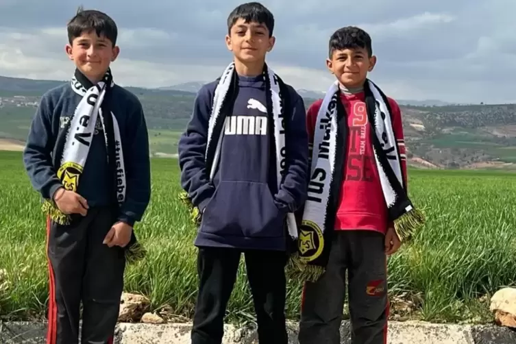 Drei türkische Jungen mit Fanschals des TuS Maikammer. 