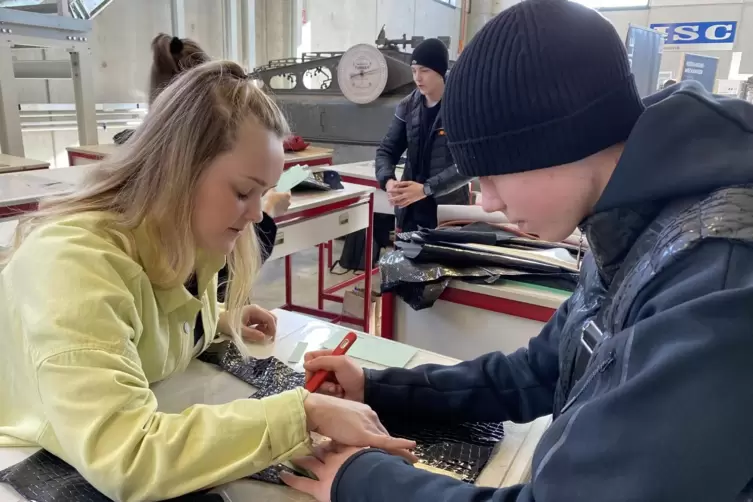 Ein erster Versuch: Michelle Ernst von der deutschen Schuhfachschule hilft Schüler Konrad Illenser, eine Handytasche zu fertigen