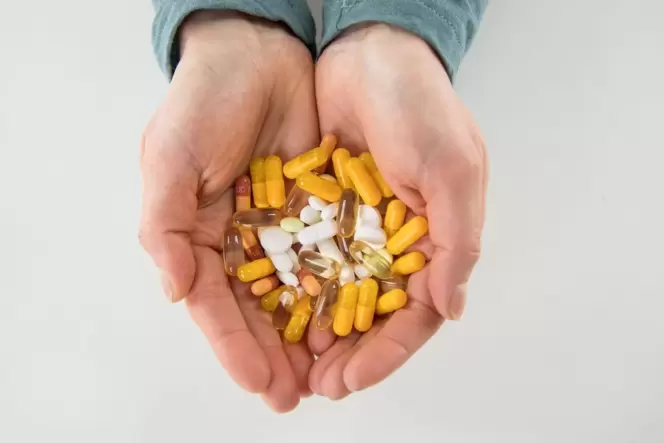 Medikamente: Mensch hält Kapseln und Tabletten in den Händen
