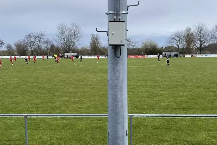 Neben dem Fußballrasen in Niederkirchen steht ein Lichtmast genau auf Höhe der Mittellinie vor dem Sprecherhäuschen.