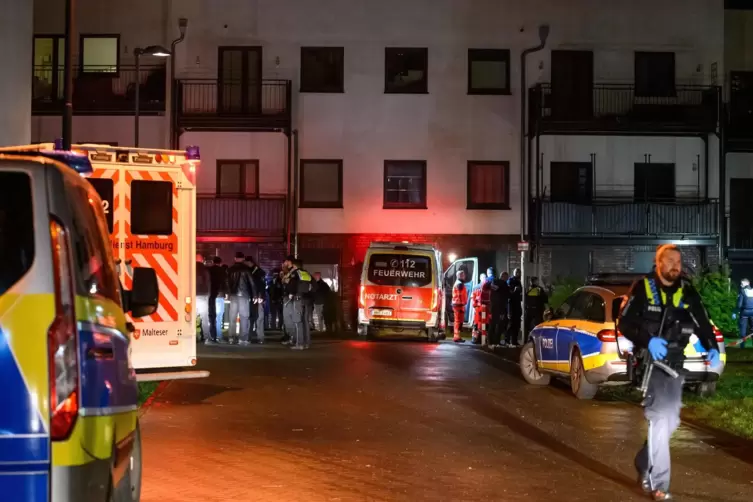 Polizisten, Ermittler und Rettungskräfte stehen am abgesperrten Tatort. Zwei Männer sind am späten Samstagabend in Hamburg-Lange