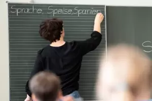 Eine Lehrerin schreibt in einer Schule Worte an eine Tafel. Eine Lehrerin schreibt in einer Schule Worte an eine Tafel.