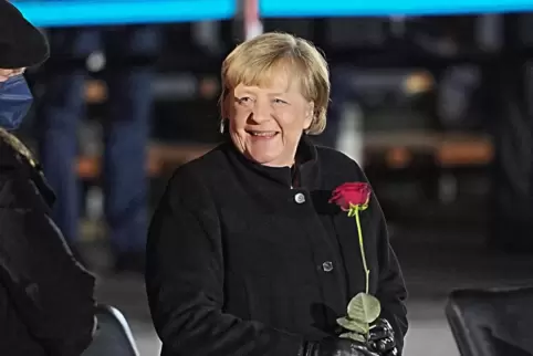 Bundeskanzlerin Angela Merkel (CDU) lacht im Dezember 2021 nach ihrer Verabschiedung durch die Bundeswehr mit einer Rosen in der