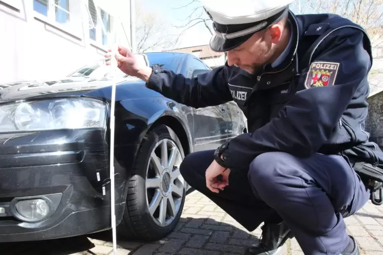 Ein Polizist dokumentiert in Landau den Schaden an einem geparkten Auto. 