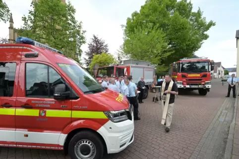 Bei der Segnung: Pfarrer Ralf Feix bespritzt die Feuerwehrfahrzeuge mit Weihwasser. 