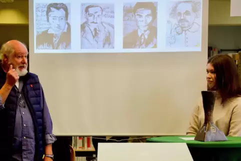 Der Fimemacher und Künstler Wilfried Saur im Gespräch mit Ida Lüthje, Schülerin der 9a, im Hintergrund Beispiele seiner Porträts
