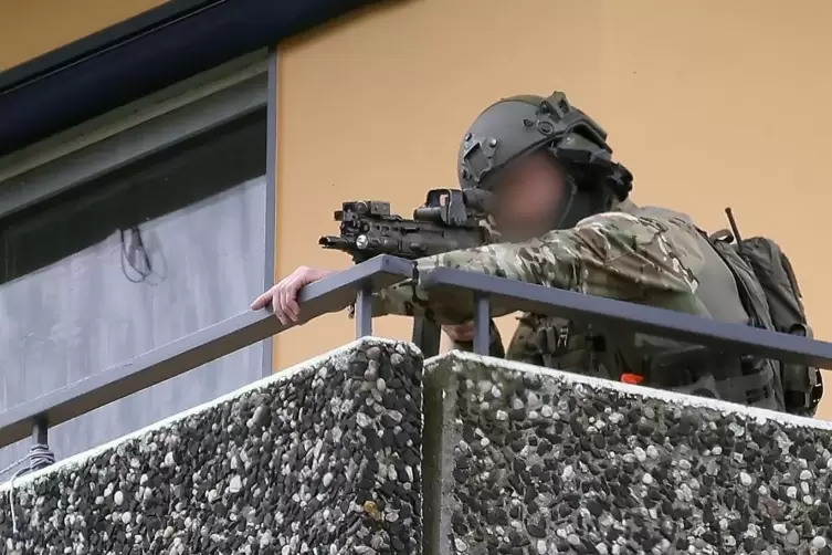 Ein Polizeibeamter in Spezialausrüstung steht auf einem Balkon und zielt mit einer Waffe. Bei einer Explosion in einem Hochhaus 