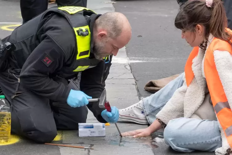 Ein Polizist versucht bei einer Straßenblockade Carla Hinrichs, Sprecherin der Klimaaktivisten, vom Asphalt zu lösen.