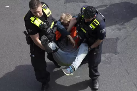 In Berlin tragen Polizisten ein Mitglied der Letzten Generation von der Straße.