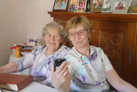Emmi Schmidt (links) und Brigitte Mannert. Sie hält das Smartphone mit Evy, die per Video-Call zugeschaltet ist.