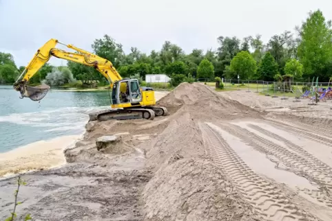 Ein Bagger schüttet Sand an der Abbruchstelle des Ufers auf. 