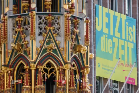 Ein Plakat zum Kirchentag mit dem Slogan „Jetzt ist die Zeit“ hängt an der Außenfassade des Rathauses in Nürnberg.