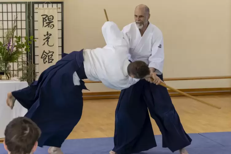 Partnerübung mit Waffen, Oliver Schröter (Mitte stehend, 5. Dan) wehrt mit dem Jo (Stab) einen Angriff mit einem Bokken/Bokute (