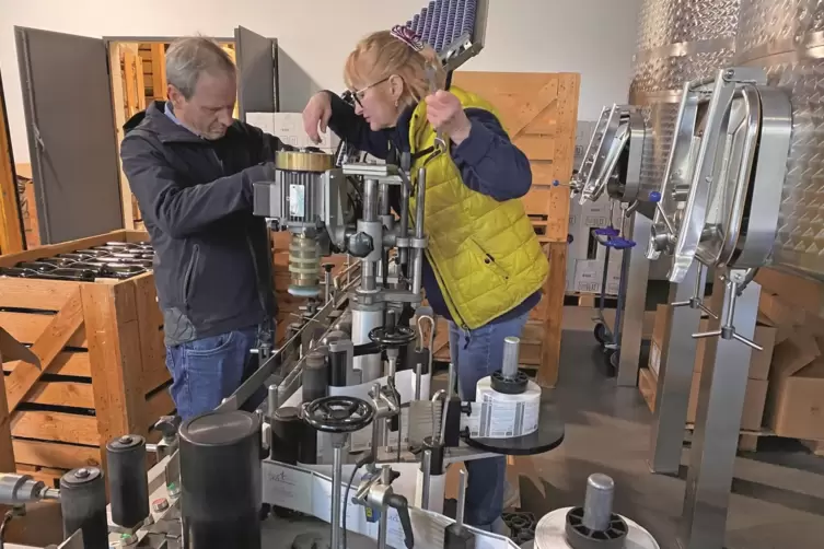 Steffen Christmann und Logistik-Mitarbeiterin Svetlana Ruf arbeiten an der Maschine zum Etikettieren der Flaschen.