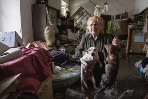 In Cherson hält eine Anwohnerin ihre Haustiere im Arm, während sie in ihrem Haus steht, das überflutet wurde. 