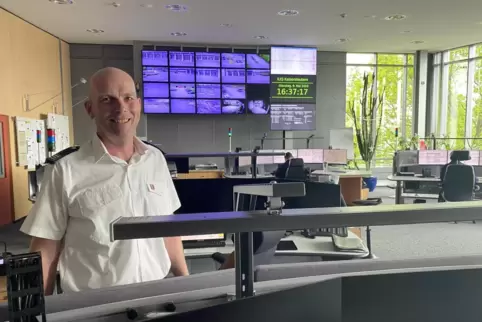 Bernd Piro von der Feuerwehr Kaiserslautern in der Integrierten Leitstelle. im Hintergrund sind zwei Disponenten bei der Arbeit 