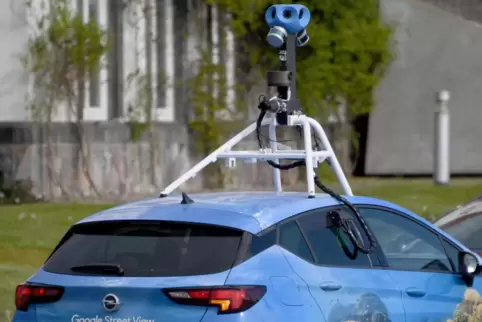 Ein Wagen von Google Street View fährt mit einer Kamera auf dem Dach durch einen Ort. 