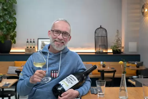 Jürgen Schmidt in seinem Restaurant mit einer Flasche „Schmidtinskis Grauburgunder“: Der Wein entstand in Kooperation mit dem We