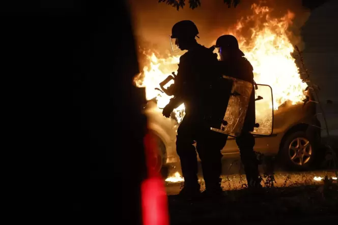 Nächtliche Krawalle: Polizisten stehen in der Nähe eines brennenden Autos im Viertel La Meinau in Straßburg.