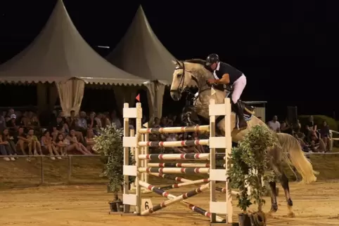 Dicht gedrängt verfolgen die Zuschauer das Barrierespringen unter Flutlicht. Hier einer von drei Siegern, Heinz Roevenich auf Ca