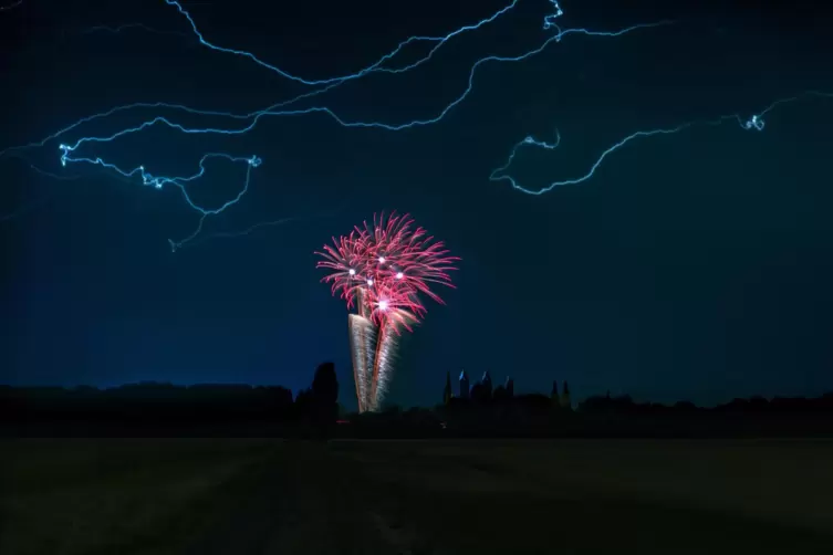 Brezelfest-Feuerwerk unter Blitzen: Aufnahme von einer Freifläche bei Hockenheim.
