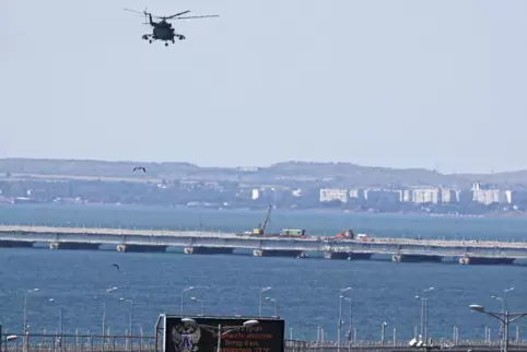Ein russischer Hubschrauber überfliegt die die beschädigten Teile einer Autoverbindung der Krimbrücke.