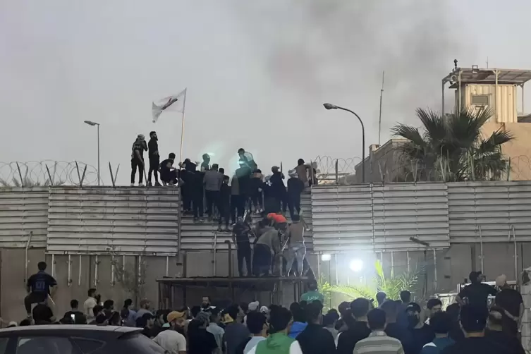 Demonstranten erklimmen eine Mauer an der schwedischen Botschaft in Bagdad.