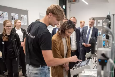 Schüler erklären Außenministerin Annalena Baerbock im Beisein von Staatssekretär Tobias Lindner (re.) wie die Smart Factory funk