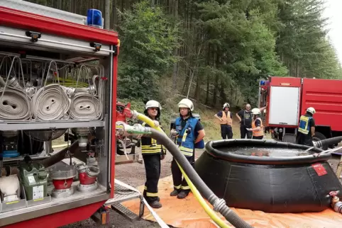 Waldbrandübung: Vorne ein Faltbehälter am Einsatzort, links am Hang „brennt“ der Wald.