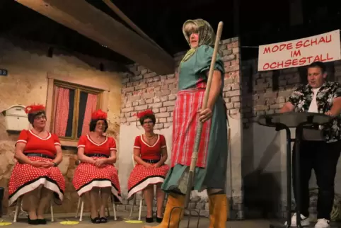 Pauline, alias Bauer Paul (Henning Bölter), führt das Modell „Landfrau“ vor, die Jurorinnen Klementine (Elfriede Lang), Gerda (A