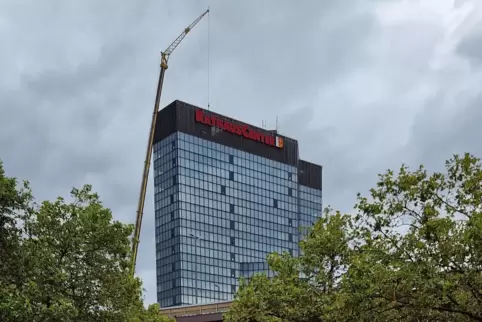 Ein Autokran hievt schwere Teile vom Dach. Die schwarzen Klappen in der Fassade dienen zur Belüftung der Etagen.