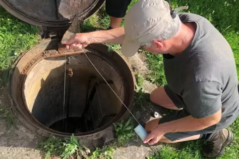 Höhlenforscher Manfred Gauda lässt eine Taschenlampe in die Zisterne am Bergfried ab. 