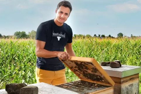 Sebastian Fischer mit seinem Bienenstock, der neben einem seiner Maisfelder steht.