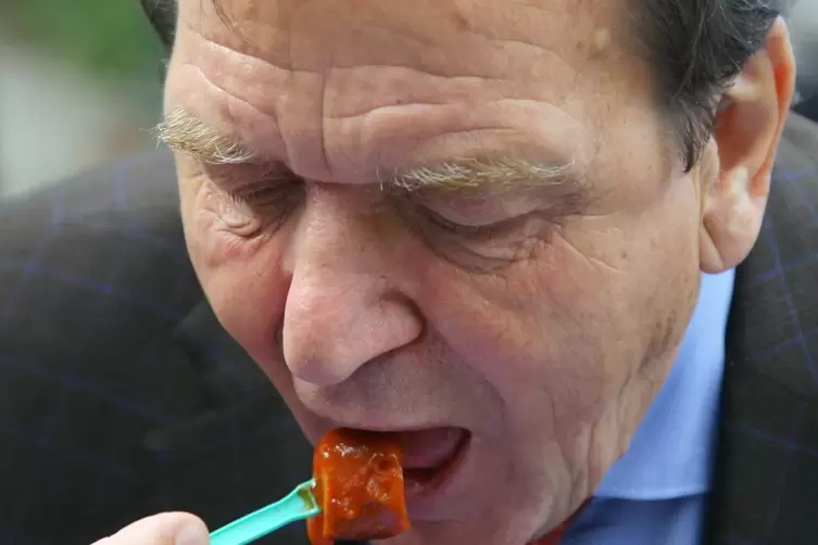 Der Altkanzler Gerhard Schröder isst eine Currywurst. 