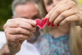Eine Frau und ein Mann halten ein Herz in den Händen.