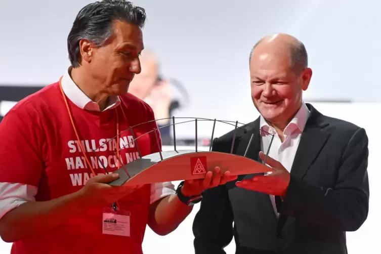 Ein Delegierter überreichte Olaf Scholz symbolisch eine Brücke, den von der IG Metall dringend geforderten Brückenstrompreis sag