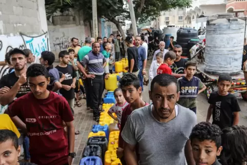 Menschen aus dem Gazastreifen warten am Grenzübergang zu Ägypten mit ihren Kanistern auf eine Wasserlieferung. 