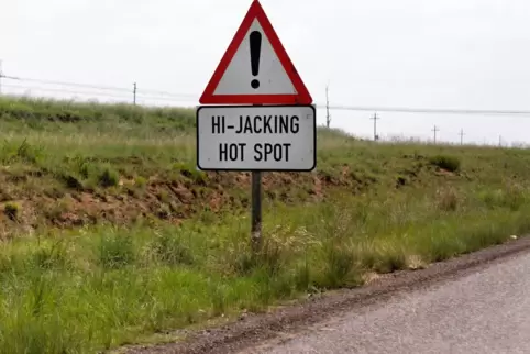 Warnschild vor Überfällen an einer Straße in Südafrika (Hi-Jacking). 