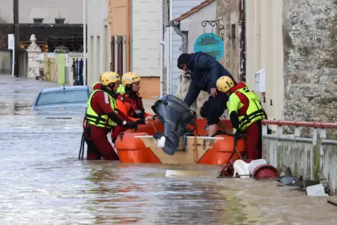 Feuerwehrleute helfen einem Anwohner auf einer überschwemmten Straße in Boulogne in ein Rettungsboot .