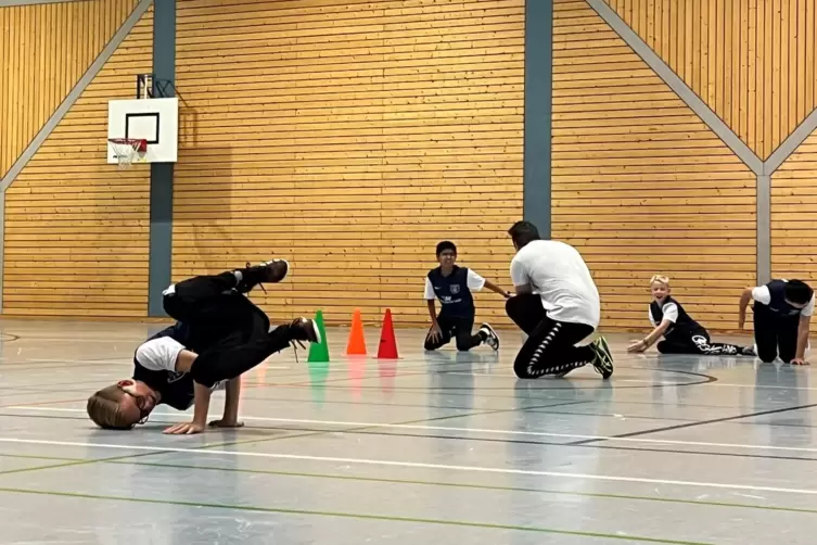 W&auml;hrend Thomas Stark seinen Mannschaftskameraden zeigt, wie sie einen &bdquo;Freeze&ldquo;, eine statische Figur, halten, &uuml;bt Leon (12) scho