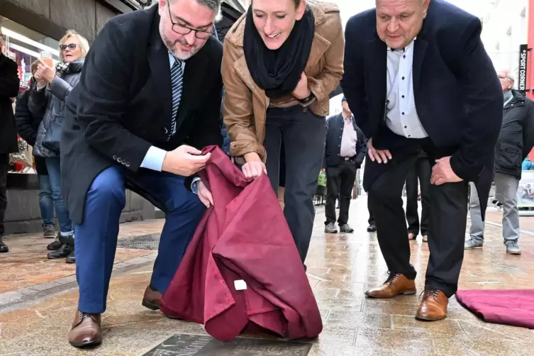 Oberbürgermeister Marc Weigel, Theresa Breuer und Christoph Meininger enthüllen gemeinsam die Bronzeplatte.