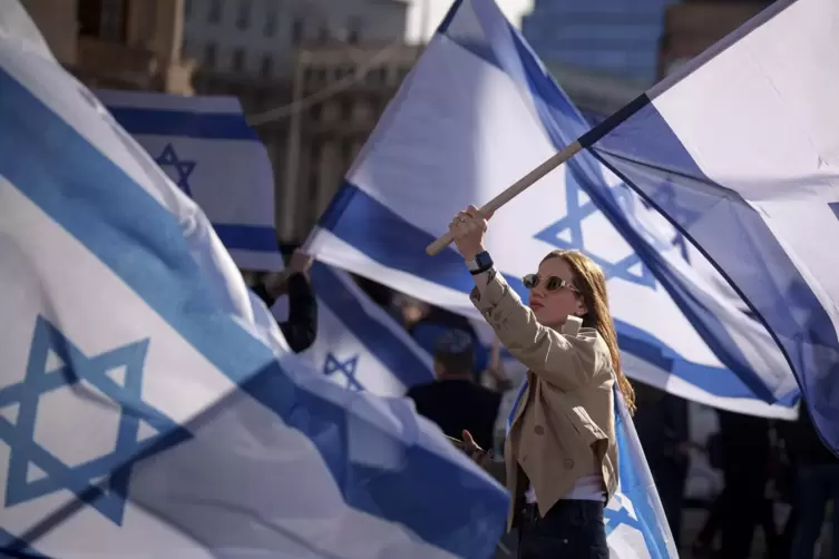Eine Frau h&auml;lt eine israelische Flagge w&auml;hrend einer Solidarit&auml;tskundgebung mit Israel und den Geiseln der Hamas