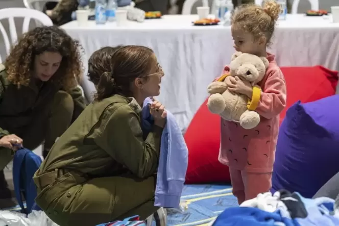 Ein freigelassenes dreijähriges Mädchen spielt mit einer israelischen Soldatin.